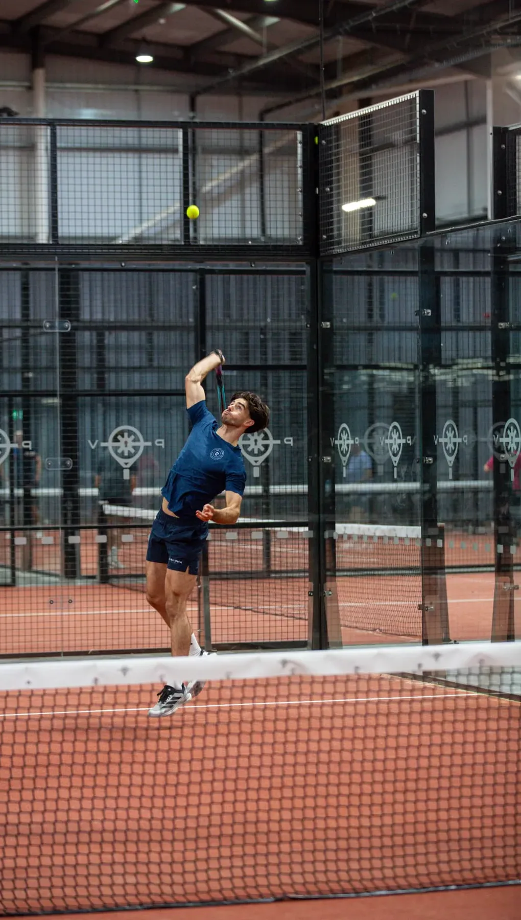 Coach Kyle hitting an overhead smash on a padel court